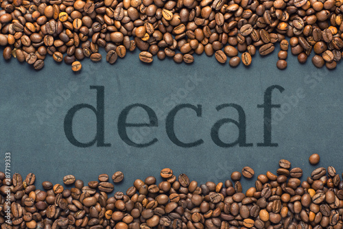 Tableau sur toile Closeup of coffee beans on grey background with the inscription decaf