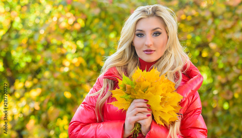 Woman spend pleasant time in autumnal park. Girl blonde makeup dreamy face hold bunch fallen maple yellow leaves. Lady posing with leaves autumnal nature background. Autumnal bouquet concept