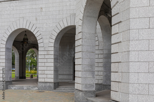Entrance to building with light grey granite tile walls and archs