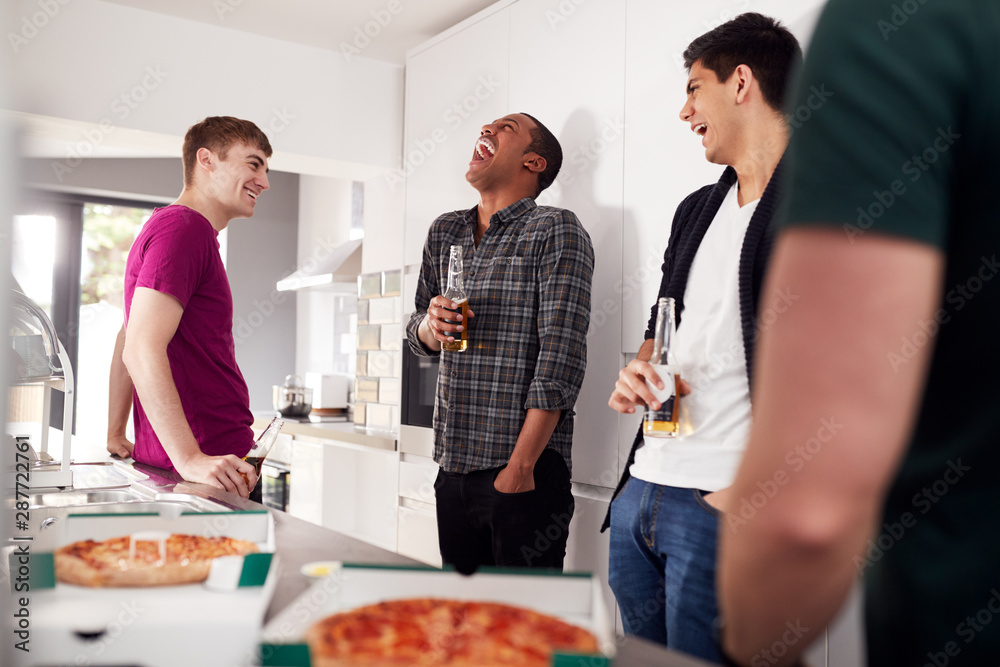 Group Of Male College Students In Shared House Kitchen Drinking Beer And Eating Pizza Together Group Of Male College Students In Shared House Kitchen Drinking Beer And Eating Pizza Together