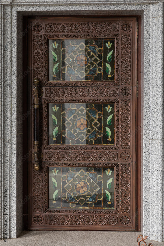 Dark brown wooden door with wood engraving and stained glass