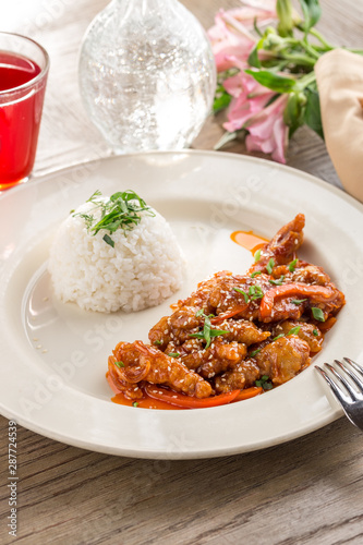 sweet and sour pork stir fried with white rice and red drink on wooden table