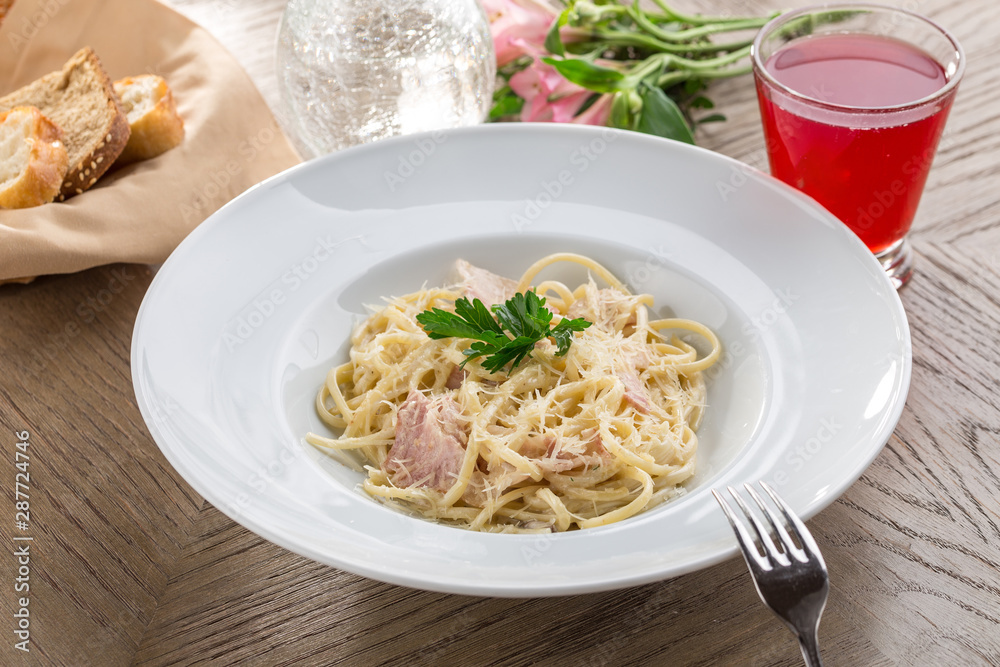 Spaghetti Carbonara with bacon and cheese and red drink on wooden table