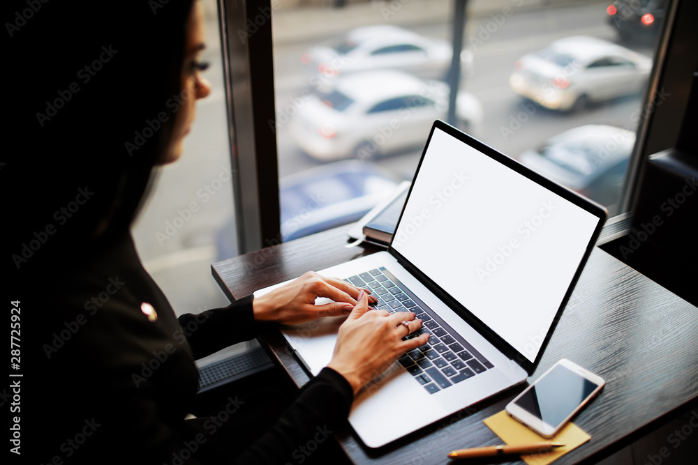 Female entrepreneur using pc laptop computer with blank monitor background with copy space for promotional content, sitting in modern interior near window with city view Female entrepreneur using pc laptop computer with blank monitor background with copy space for promotional content, sitting in modern interior near window with city view