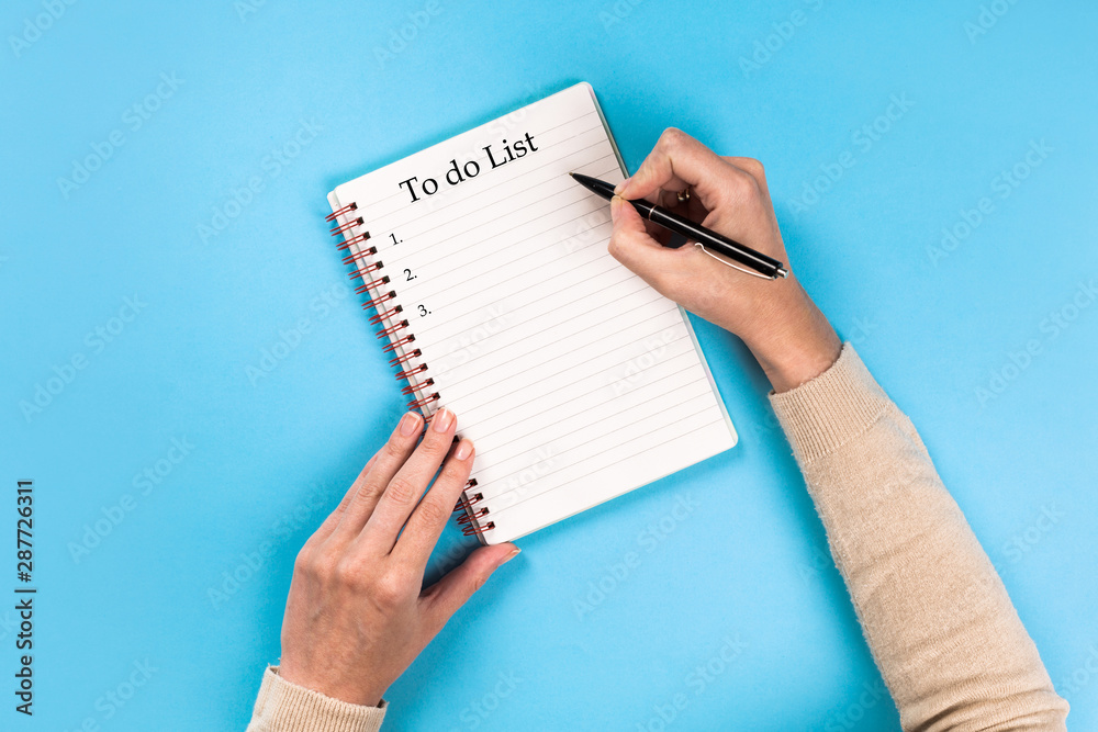 To do list Concept - 2020 number and text on notepad. Woman's hands with perfect manicure holding pencil and notepad as mockup for your design. blue background, flat lay style. To do list Concept - 2020 number and text on notepad. Woman's hands with perfect manicure holding pencil and notepad as mockup for your design. blue background, flat lay style.
