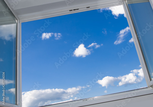 An open window overlooking the urban landscape on a sunny cloud day