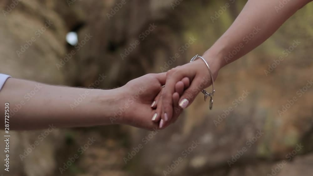 A man and a woman are holding their hands with the rocks in the background