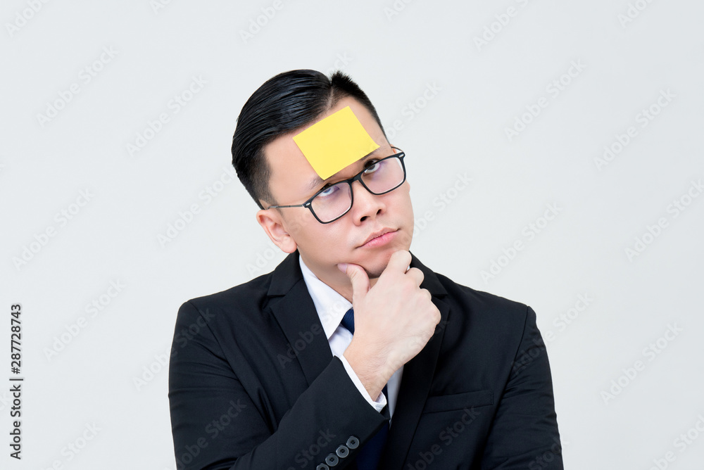 Bored businessman thinking with sticky note paper on forehead Bored businessman thinking with sticky note paper on forehead
