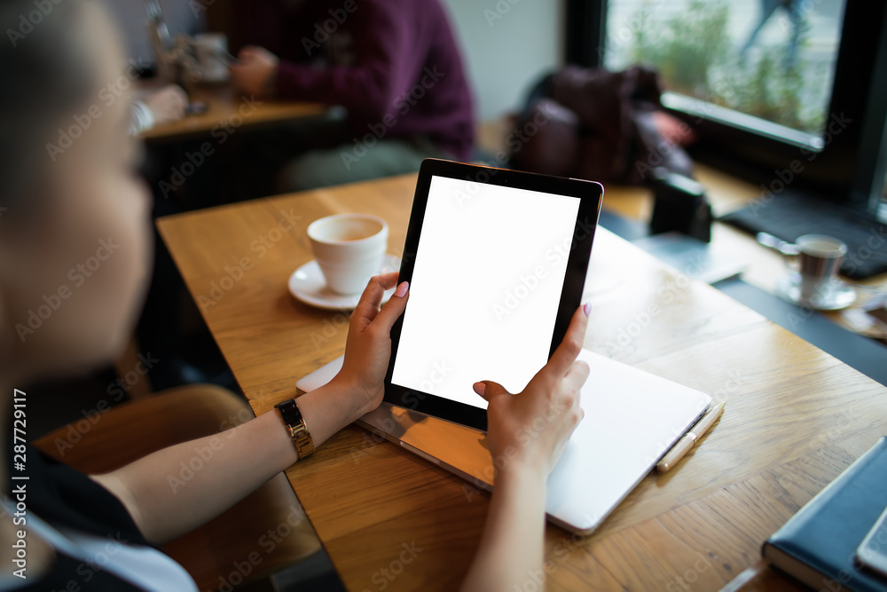 Business woman using portable touch pad with empty mock up copy space screen background for promotional content, sitting at table in coffee shop. Hipster girl using digital gadget with blank display Business woman using portable touch pad with empty mock up copy space screen background for promotional content, sitting at table in coffee shop. Hipster girl using digital gadget with blank display