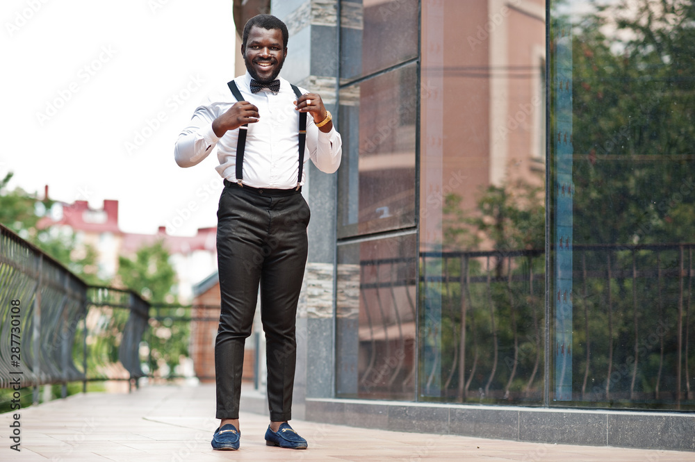 Handsome fashionable african american man in formal wear, bow tie and  suspenders, walking stick. Stock Photo