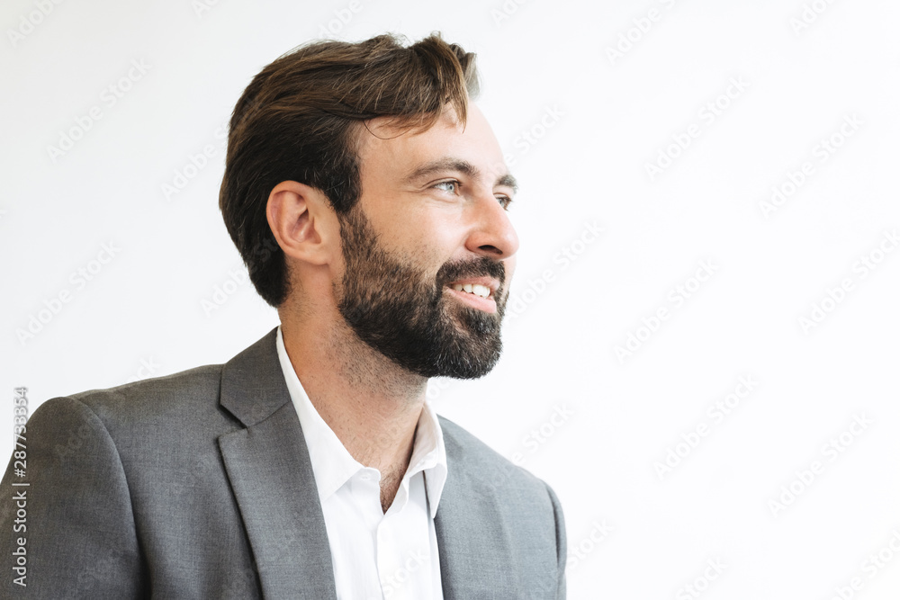 Image closeup of bearded successful businessman smiling and looking aside while working in office Image closeup of bearded successful businessman smiling and looking aside while working in office