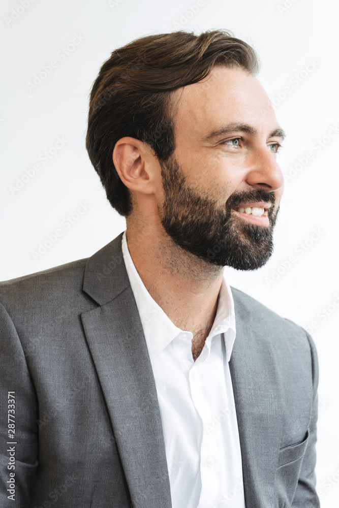 Image closeup of happy successful businessman smiling and looking aside while working in office Image closeup of happy successful businessman smiling and looking aside while working in office