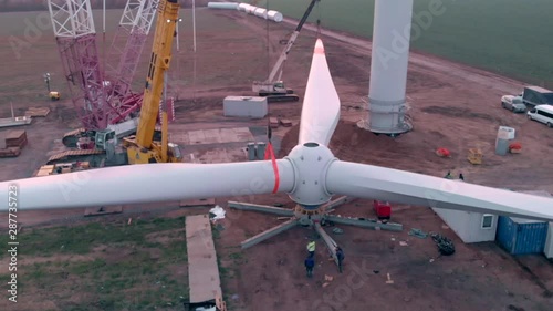 Building process of wind energy power tower mill, under construction. Assembling blades, turbine, rotor. Green, clean, renewable energy. Aerial footage.