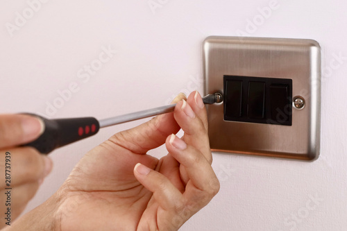 A female electrician fitting a light switch
