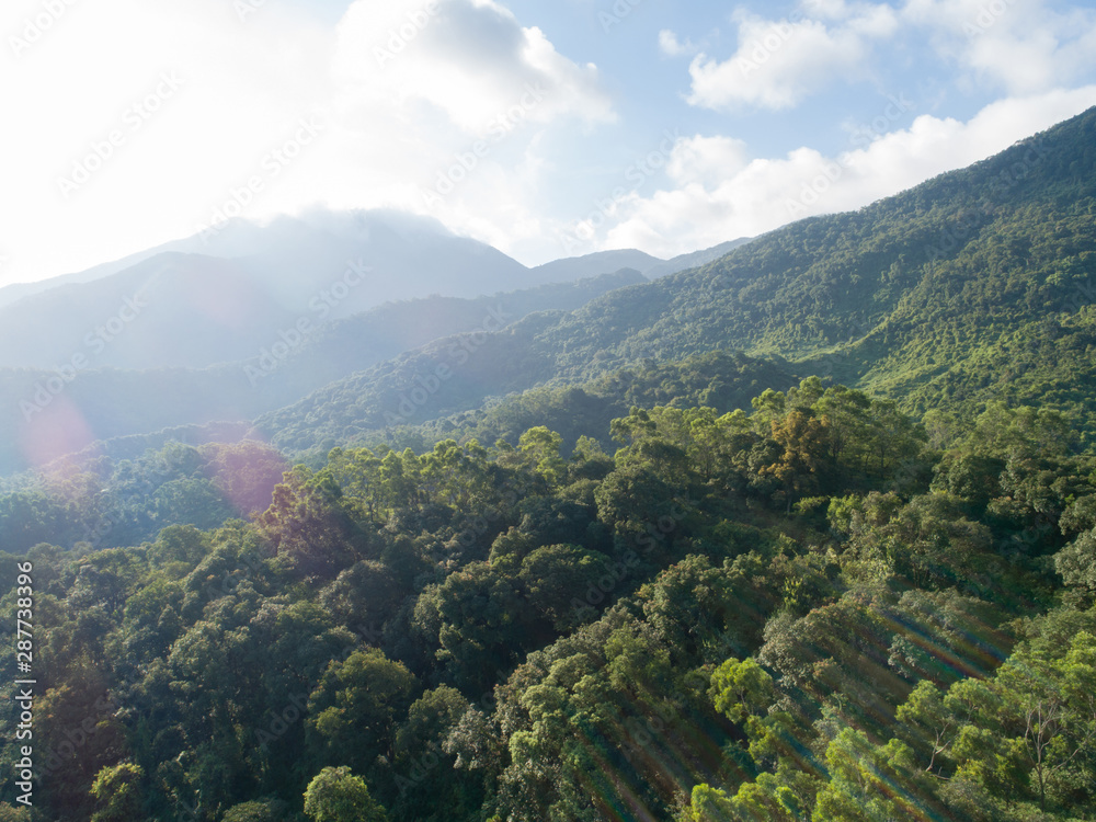 Aerial view of mountains with green dense tropical rainforests and morning fog in the sunrise