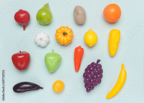  Toy plastic imitations (fake) of different vegetables and fruits on a blue background. Visual material for educating children and expanding their understanding of the world.