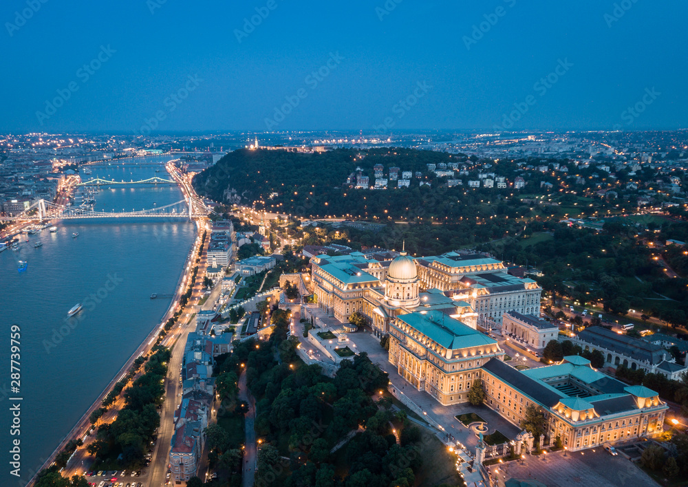 Budapest, Hungary - Aerial panoramic view of the beautiful Buda Castle Royal Palace at night with Gellert Hill and Statue of Liberty at background over Danube river