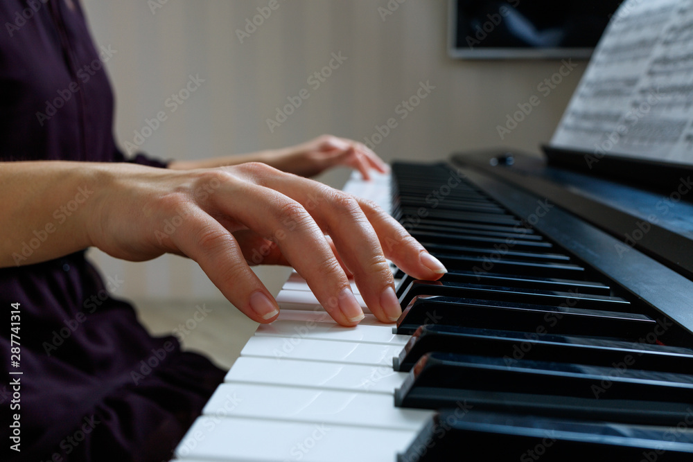 Fototapeta premium Young woman playing piano