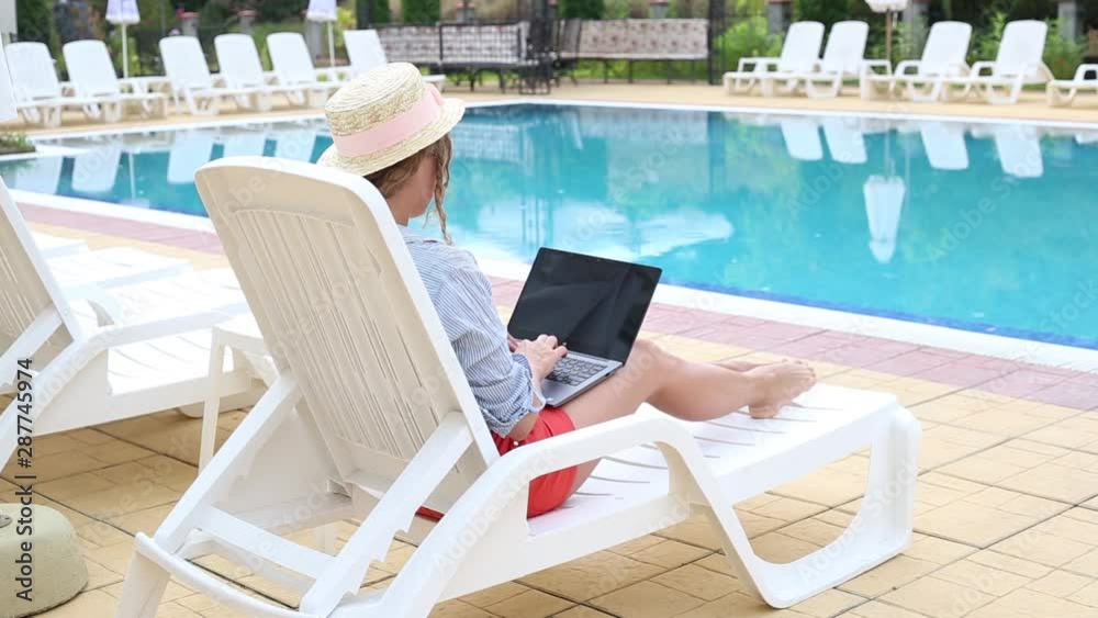 Creative freelancer working on computer in the background of swimming pool Creative freelancer working on computer in the background of swimming pool