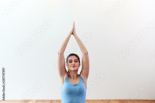 Fototapeta Naklejka Na Ścianę i Meble -  Young Woman Doing Yoga On Wooden Floored Studio At Home