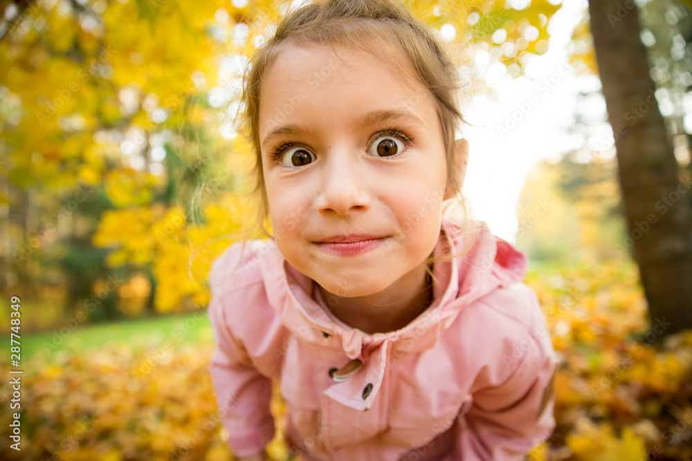 Cute little girl making funny faces into the camera Happy child laughing and smiling. Sunny autumn forest, sun beam. Cute little girl making funny faces into the camera Happy child laughing and smiling. Sunny autumn forest, sun beam.