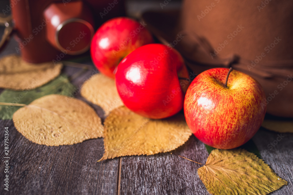 autumn red apples on wooden table and hat