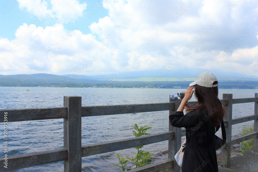 A woman is taking a photo in front of beautiful lake.