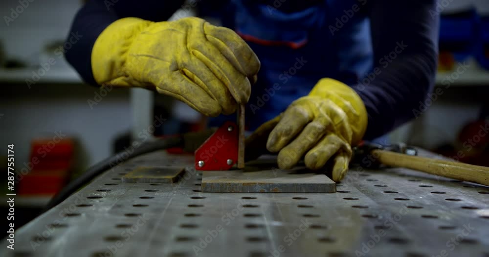 Close-up portrait of a gloved hand of a welder who works with the Assembly of a part for welding. Close-up portrait of a gloved hand of a welder who works with the Assembly of a part for welding.