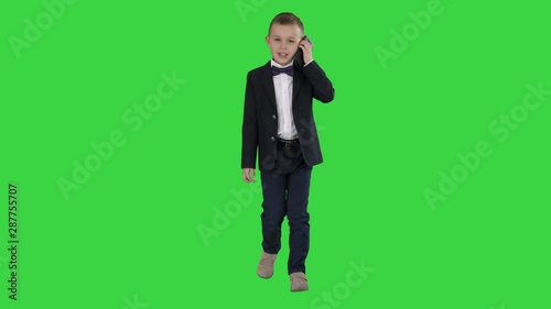 Little boy in a costume making a phone call while walking on a Green Screen, Chroma Key. photo