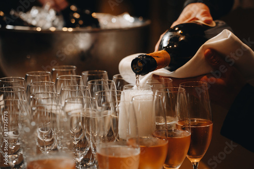 Pouring champagne into wine glasses. Champagne flutes on a wedding or new year eve party photo
