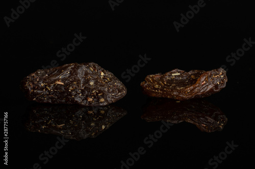 Group of two pieces of raisin of lingonberry strawberry fruit tea macro isolated on black glass