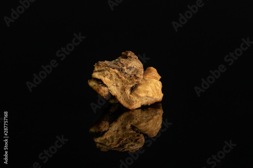 One piece of roseship of lingonberry strawberry fruit tea macro isolated on black glass