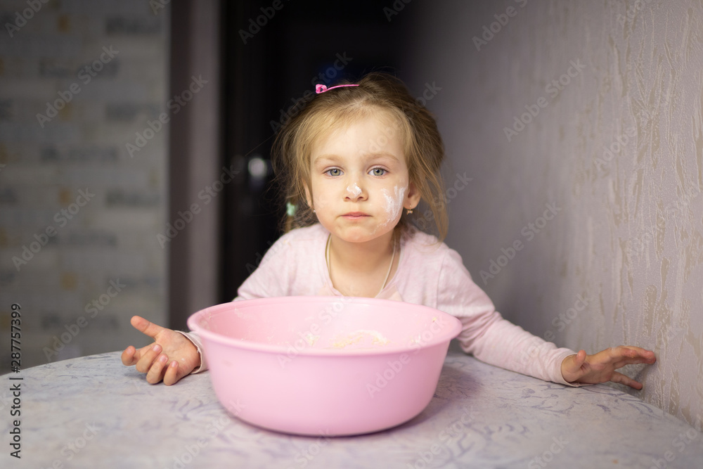 A child plays with flour and dough. daughter helps to cook. Floured baby face. Children's emotions A child plays with flour and dough. daughter helps to cook. Floured baby face. Children's emotions