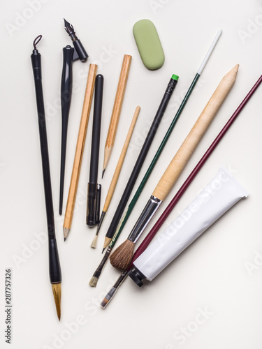 Brushes, pens and pencils on a white background. Flat lay