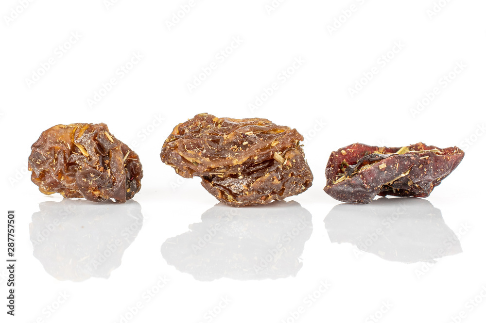 Group of three pieces of raisins of lingonberry strawberry fruit tea macro isolated on white background Group of three pieces of raisins of lingonberry strawberry fruit tea macro isolated on white background