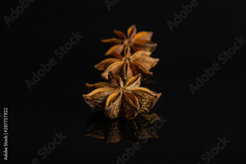 Group of three whole dry brown star anise illicium verum isolated on black glass