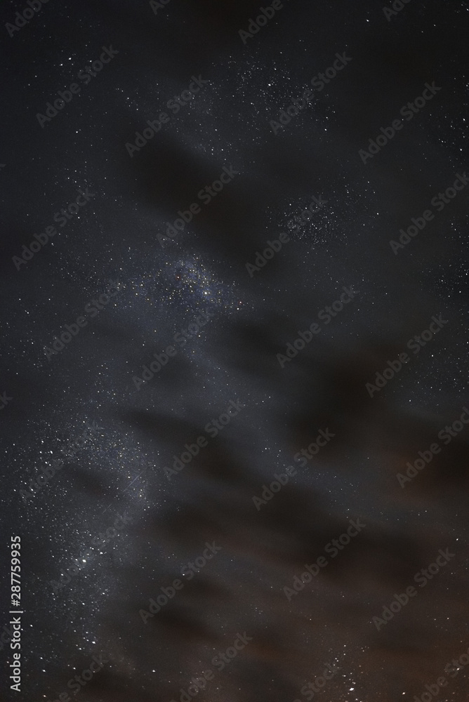 Fototapeta premium Milky way in the night sky through the clouds on a summer night