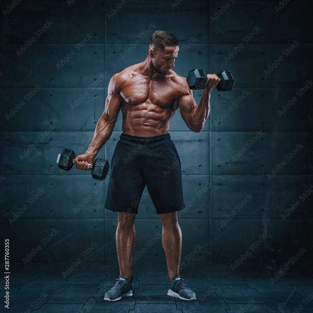 Muscular Men Exercise With Weights. He is performing bicep curls with dumbbels