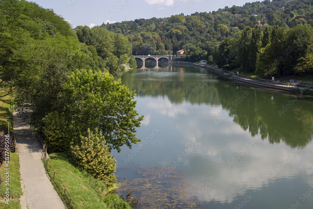 Fototapeta premium The river Po in Turin, Italy, seen from the Valentino park on the Franco Balbis bridge with the Isabel bridge in the background.