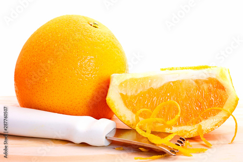 An orange with a zester getting out the zest off against white isolated