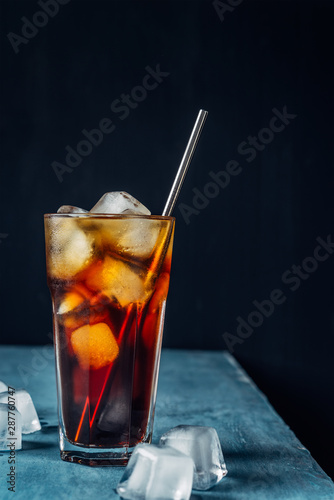 Billede på lærred Cold brew coffee in a glass with metal straw on a dark background