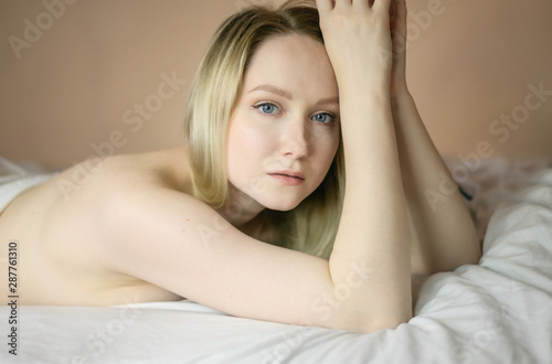 Closeup portrait of a beautiful young lady lying on the bed.