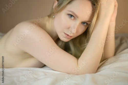 Closeup portrait of a beautiful young lady lying on the bed.