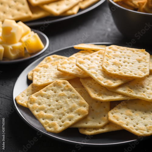 Crackers with cheese and greens on a dark background.