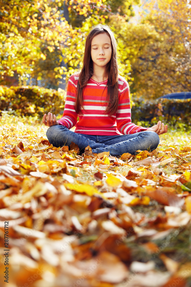 teenage girl meditating in the autumn park teenage girl meditating in the autumn park
