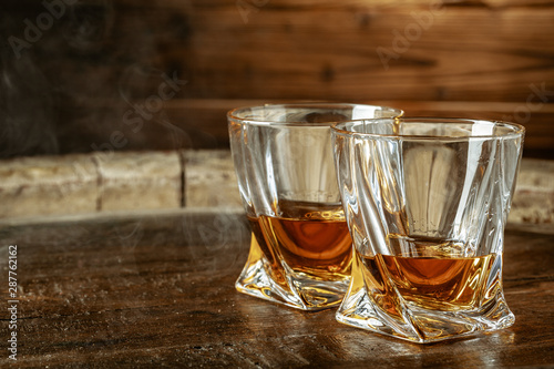 A bottle of cognac and glass on a brown wooden background. Brandy