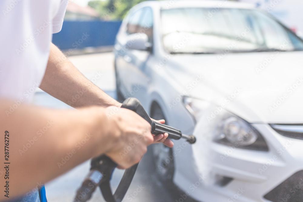 Close up of man washing his car with pressurized water in car wash outdoors.