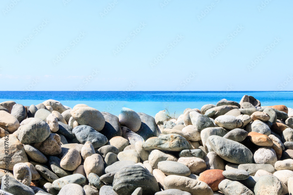 large pebbles against the sea and blue sky.