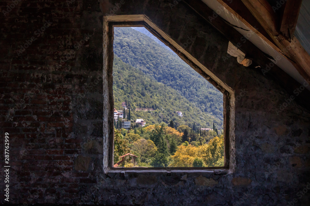 Fototapeta view from the old stone window to the mountains and forest