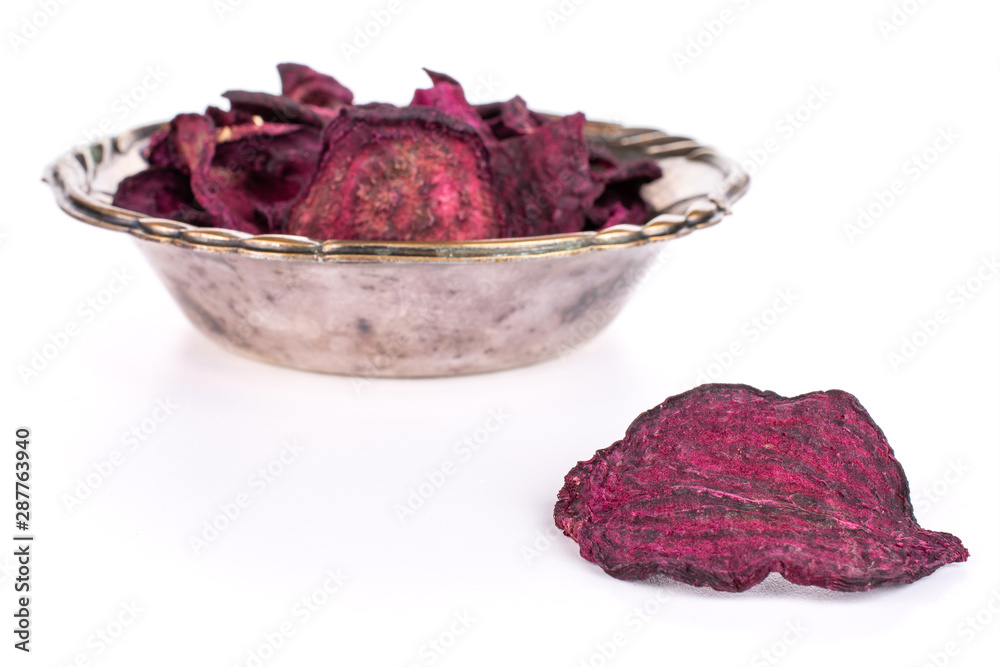 Obraz premium Lot of slices of dried red beetroot one is in the front and the rest is in metal bowl isolated on white background